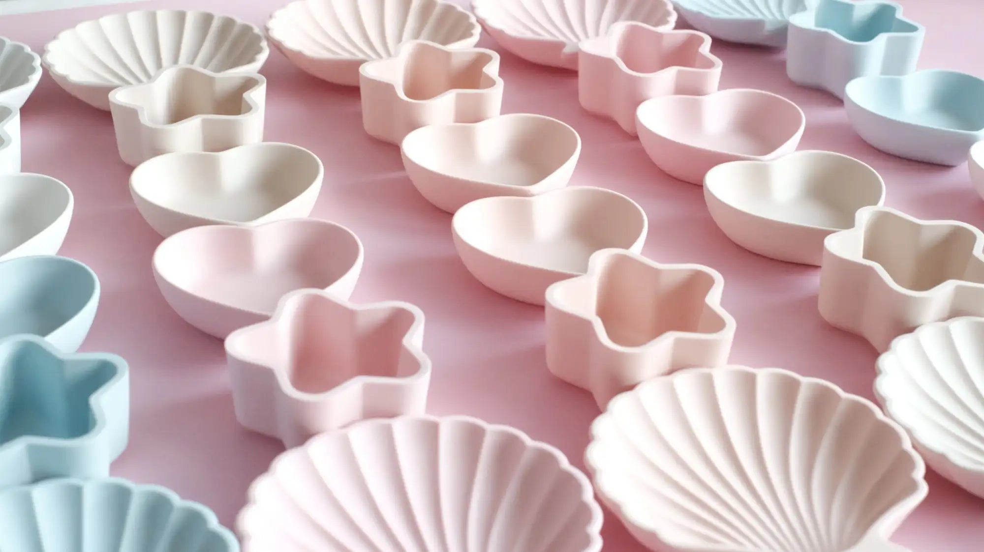 Pastel pink and white ceramic dishware shaped like seashells, hearts, and stars.